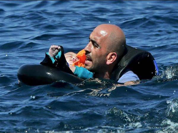 صورة لاجئ سوري يحمل إبنه تهز ضمير العالم في عرض البحر!