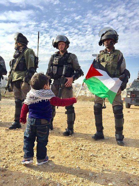 طفل فلسطيني لا يهاب  جنود الاحتلال ويحمل علم فلسطين