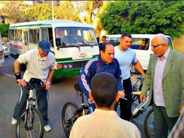 بالصور- السيسي يتجول بملابس رياضية على دراجة هوائية في شوارع القاهرة 